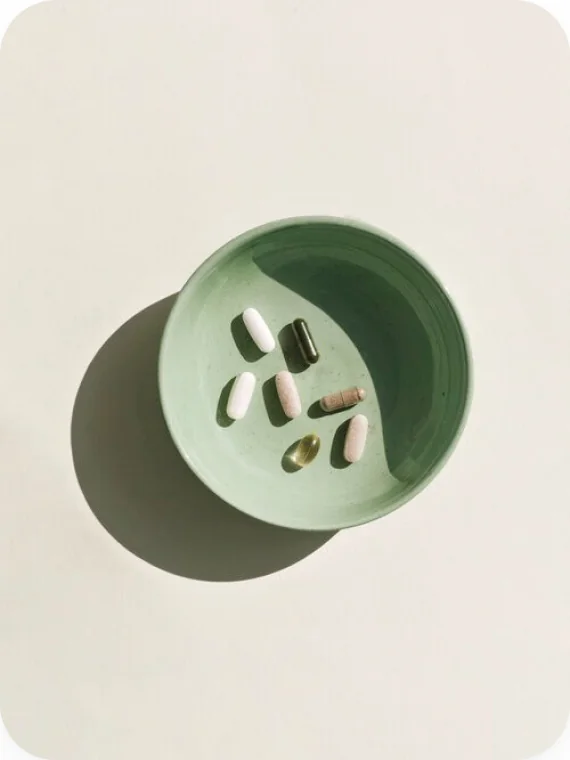 Vitamin capsules in a sage bowl, shot from above